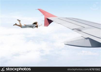 On wing of flying airplane. Young businesswoman flying on edge of airplane wing