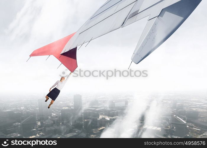 On wing of flying airplane. Young businesswoman flying on edge of airplane wing