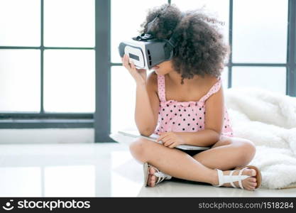 One African mixed race girl enjoy with VR glasses and also hold laptop in the room with day light.