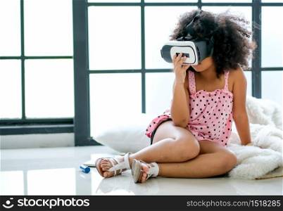 One African mixed race girl enjoy with VR glasses and sit on floor in the room with day light.