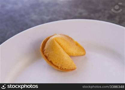 One, Asian fortune cookie sits on white plate on marble table top. Simple image of fortune&rsquo;s choice with copy space around.