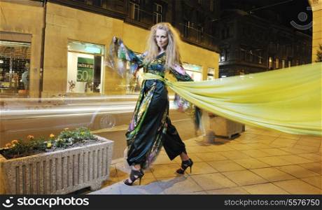 one beautiful young elegant woman in fashion and urban style dress in city on street at night alone