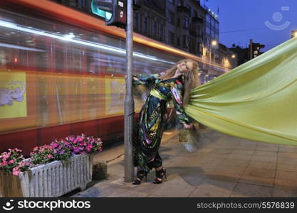 one beautiful young elegant woman in fashion and urban style dress in city on street at night alone