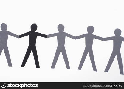 One black cutout paper person holding hands with group of white people.