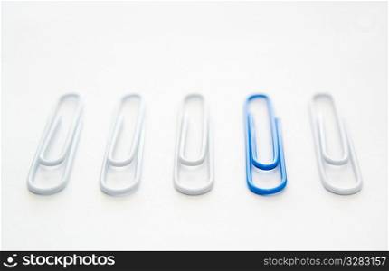 One blue paper clip included in group of white ones.
