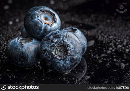One blueberries covered with water drops isolated on black background. Copy space for text. Selective focus. One blueberries covered with water drops isolated on black background.