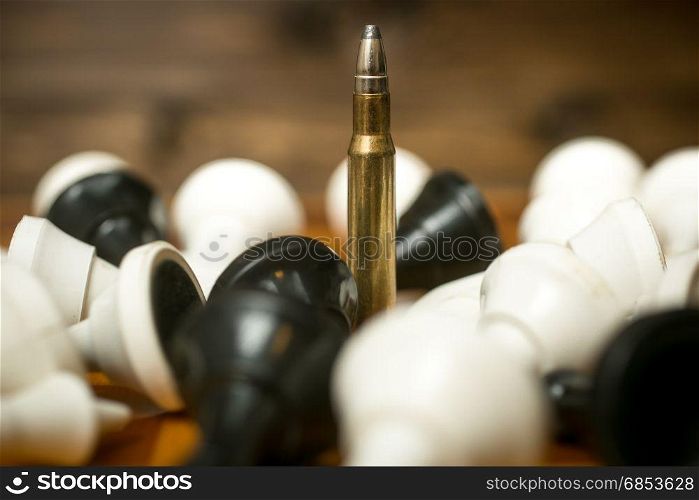 One bullet among lying chess pieces. Concept of military power
