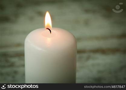 One burning Christmas candle on a white wooden background