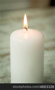 One burning Christmas candle on a white wooden background