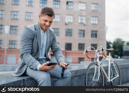 One businessman poses with bicycle at the office building in downtown. Business person riding on eco transport on city street