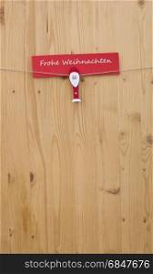 One christmas man with clothes pegs on a cord on wood and german text for merry christmas