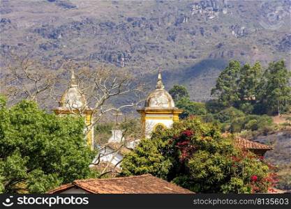 One church tower of the many historic churches in baroque and colonial style from the 18th century amid the hills and vegetation of the city Ouro Preto in Minas Gerais, Brazil. Historic church tower in baroque and colonial style from the 18th century amid the hills and vegetation