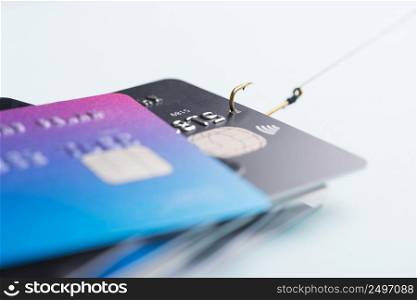 One credit card being stolen by fishing hook from pile of other bank cards, fraud data leak money stealing phishing concept