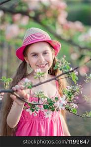 One cute girl in the garden with blooming cherries and apple trees, a girl playing outdoors.. One cute girl in the garden with blooming cherries and apple trees.