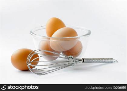 One egg on the table, four eggs in a glass cup, a whip