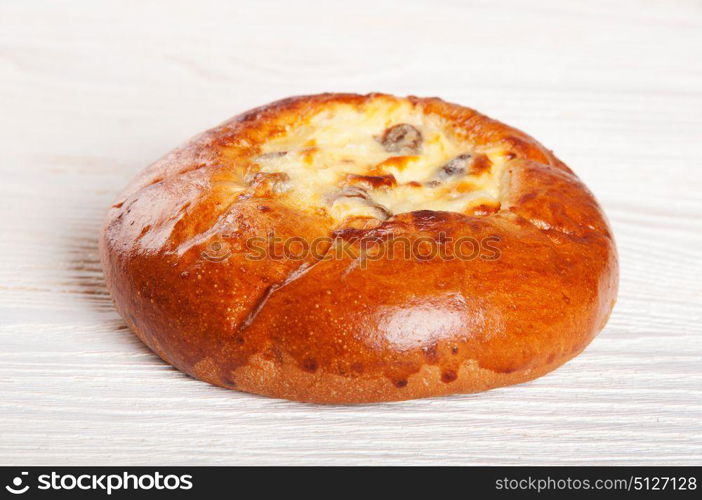 One fresh homemade bun with cottage cheese and raisins on a wooden table
