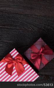One gift box with an red big ribbon on old wooden dark brown background for christmas, close up view holidays concept, orizontal version