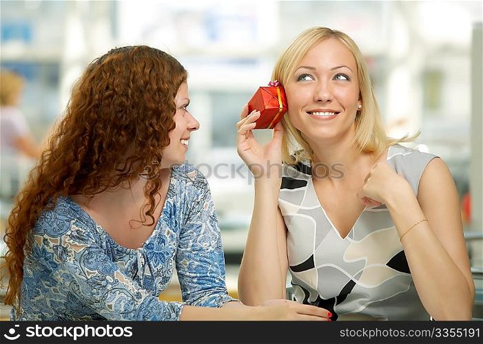 One girl gives a gift another in cafe