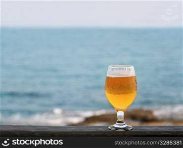 one glass of beer against sea and coastline