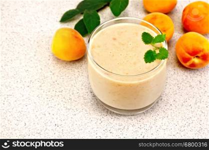 One glass of milkshake with apricots, mint on the background of a granite table