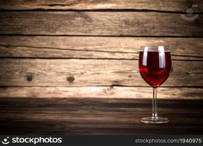 One glass of red wine. On a wooden background. . One glass of red wine.