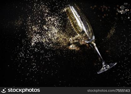 One glass with Christmas amd Happy New Year Champagne and glitter over black background. Christmas amd Happy New Year Champagne