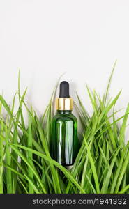 One green glass bottles with serum, essential oil, collagen or other cosmetic product among the green grass on white background. Natural Organic Spa Cosmetic concept Mockup Top view.. One green glass bottles with serum, essential oil, collagen or other cosmetic product among the green grass on white background. Natural Organic Spa Cosmetic concept Mockup Top view