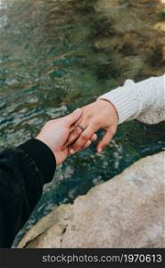One hand grabbing another hand with a river as the background using a rubber ring love concept