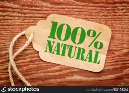 one hundred percent natural sign - a paper price tag against rustic red painted barn wood - shopping concept