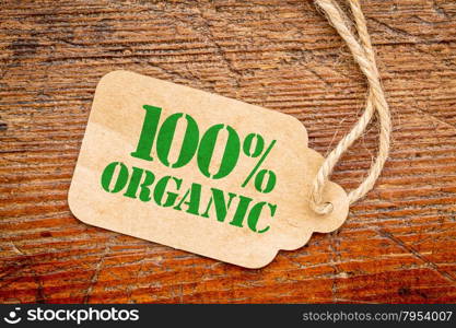 one hundred percent organic sign - a paper price tag against rustic red painted barn wood - shopping concept