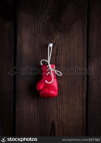one leather red boxing glove with laces on a brown wooden background