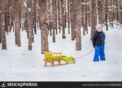 One little girl with sled in the forest. Family winter walk in the woods.. One little girl with sled in the forest. Family walk in the woods.
