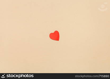 one little heart cut out of red paper on background from yellow navajo white pastel paper