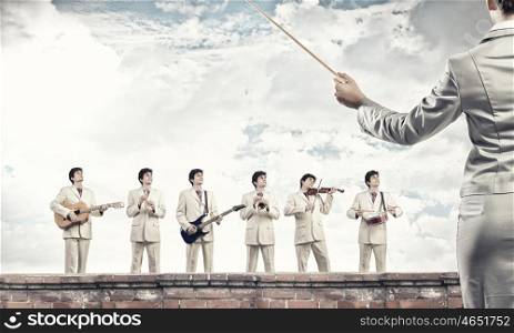 One man band. Man orchestra playing different music instruments and woman leader