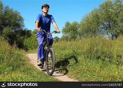 one man wearing sporty clothes is riding on a bycicle and looking at camera. sunny summer day.