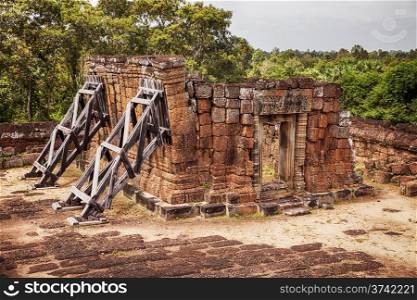 One of the four corner buildings of the East Mebon temple has walls that are leaning over that are shored up with wood supports.