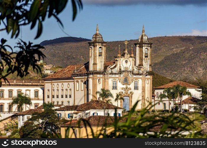 One of the main historic churches in the city of Ouro Preto seen through the vegetation with the mountains in the background. One of the main historic churches in the city of Ouro Preto