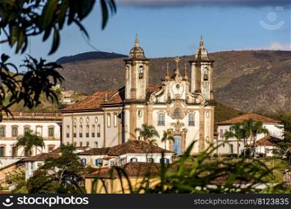 One of the main historic churches in the city of Ouro Preto seen through the vegetation with the mountains in the background. One of the main historic churches in the city of Ouro Preto