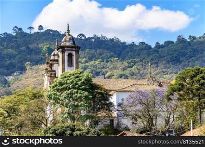 One of the many historic churches in baroque and colonial style from the 18th century amid the hills and vegetation of the city Ouro Preto in Minas Gerais, Brazil. Historic church in baroque and colonial style from the 18th century amid the hills and vegetation