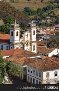 One of the many historic churches in baroque and colonial style from the 18th century amid the houses and roofs of the city Ouro Preto in Minas Gerais, Brazil. Historic church in baroque and colonial style from the 18th century amid the houses and roofs