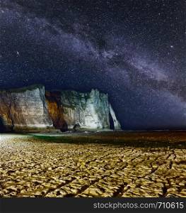 One of the three famous white cliffs known as the Falaise de Aval. Etretat, France. Starry night scene with Milkyway galaxy in sky.