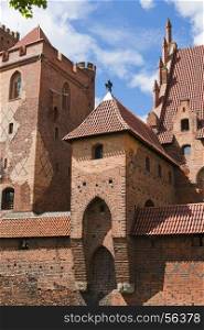 One of the towers of the largest brick castle (Malbork) with a metal statue filinayu Poland