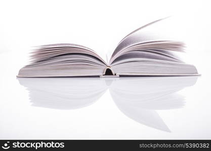 One open white book with reflection on white