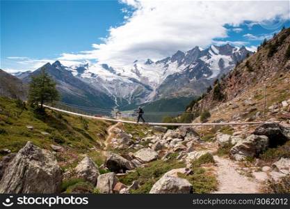 one person young man walking on a suspension bridge in Switzerland, hiking with a beautiful landscape