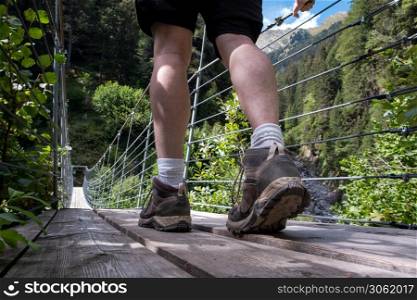 one person young man walking on a suspension bridge in Switzerland, hiking with a beautiful landscape traveling. one person young man walking on a suspension bridge in Switzerland, hiking with a beautiful landscape