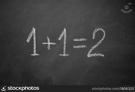 One plus one equals two hand written on chalkboard. Math simple equation. Top view