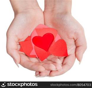 one red heart above pile of paper hearts on female palms isolated on white background