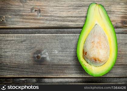 One ripe avocado cut with bone. On a dark wooden background.. One ripe avocado cut with bone.