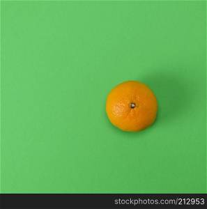 one ripe orange tangerine peel on a green background, close up, empty space