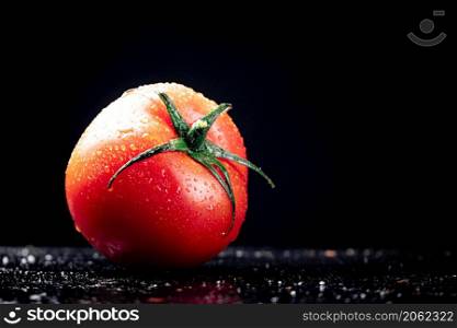 One ripe tomato on the table. On a black background. High quality photo. One ripe tomato on the table.